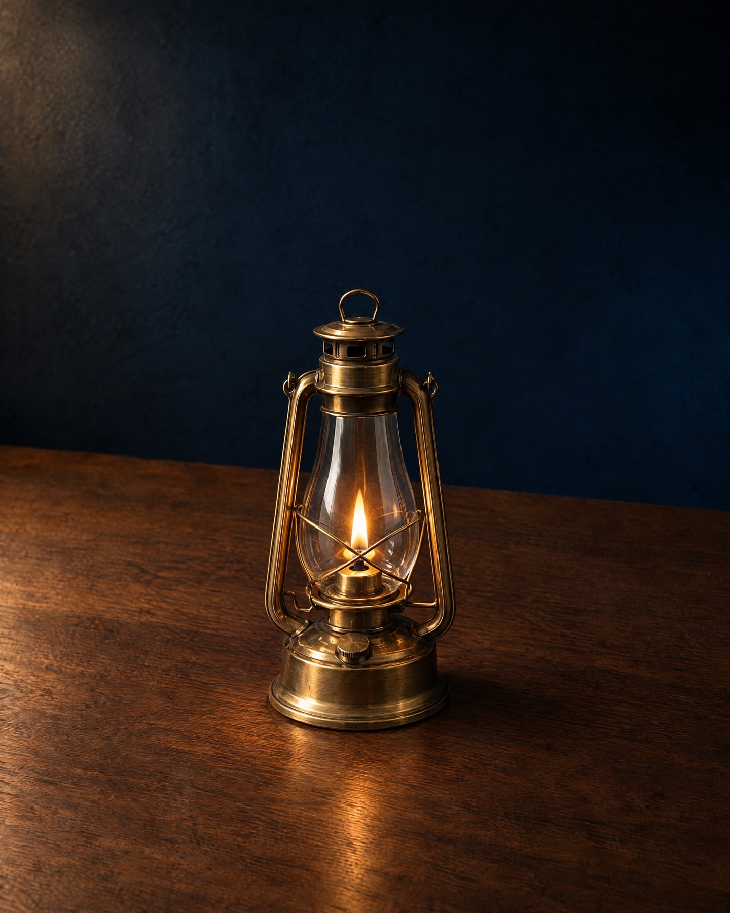 A brass hurricane lantern, lit, on a walnut table